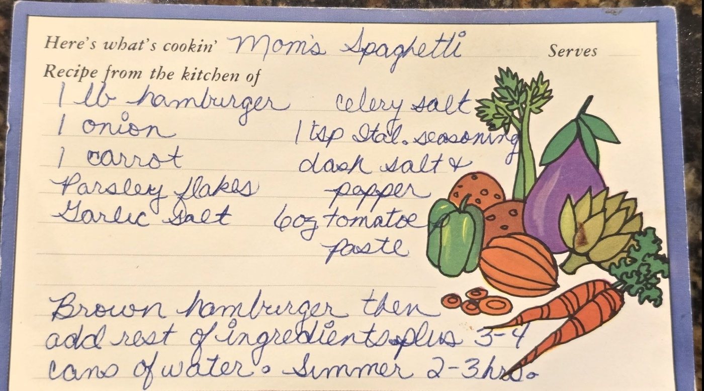A recipe card for Mom's Spaghetti, handwritten in blue ink on printed “Here's what's cookin'” stationery